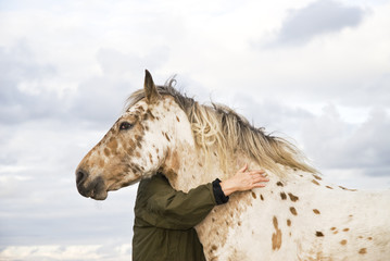Woman hugging an appaloosa horse