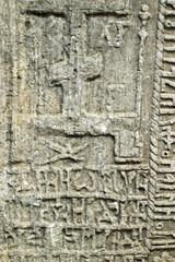 Grungy ancient tombstone with old inscriptions and cross