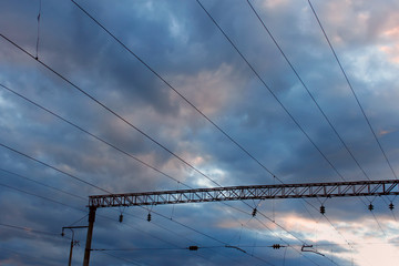 Power line of electric trains against the cloudy sky