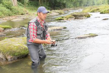 Fisherman in river with fishing rod