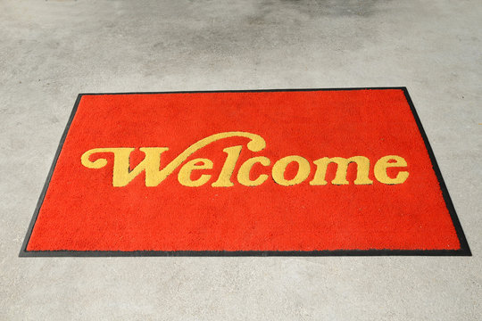 A Red Welcome Mat With Golden Letterings