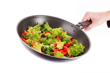 frying pan with vegetables  in hand on white