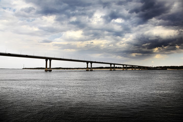 Fototapeta na wymiar Most przez rzekę i szerokich burzowe chmury.