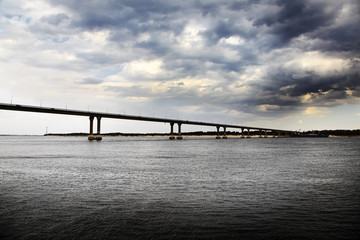 Bridge across the wide river and storm clouds.