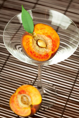 peach with a leaf and a martini glass on a bamboo mat