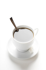 cup of coffee with teaspoon and sugar slices isolated on white