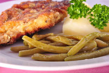 paniertes Schnitzel mit Salzkartoffel und Bohnen