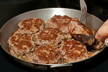 Danish meat balls being turned on the frying pan
