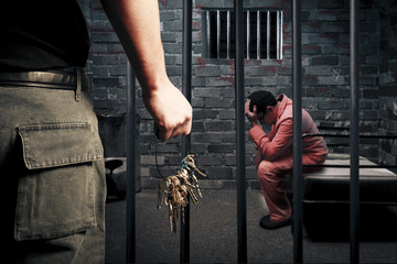 prison guard with keys outside dark prison cell