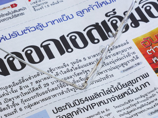 Close-up of Thai language newspaper and a pair of glasses.