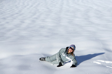Fototapeta na wymiar Jeune femme souriante couchée dans la neige