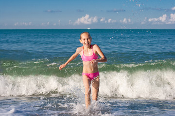 Close-up girl running from sea wave