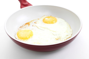 Broken egg frying in a pan isolated on white