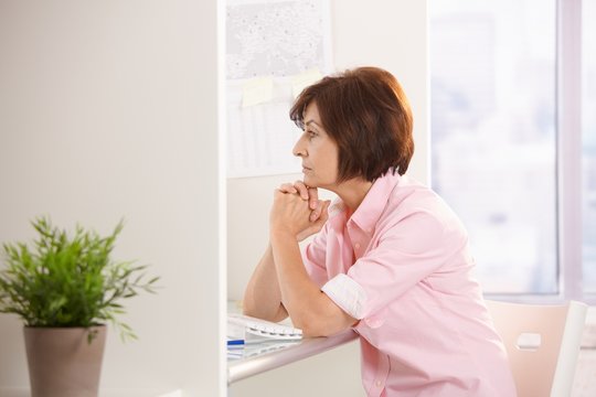 Mature female office worker thinking at desk