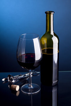 Glass of red wine with bottles on a blue background
