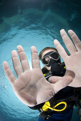 Male scuba diver showing his handpalms, focus on face.