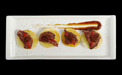 An appetizer of meat on potato chips with ketchup