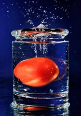 Fotobehang Rode tomaat valt in glas met water op diepblauw © HamsterMan