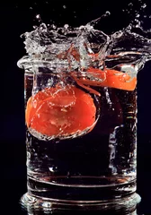 Poster Rode tomaat valt in glas met water op diepblauw © HamsterMan