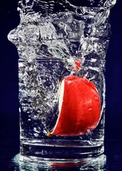  Schijfje rode appel vallen in glas met water op diepblauw © HamsterMan