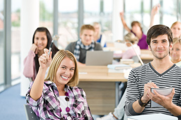 High school student raising hands in classroom