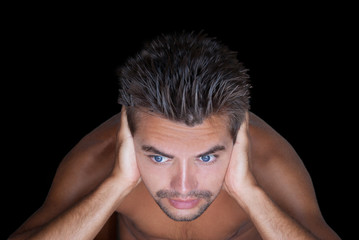 Guy naked torso shut ears against the black background