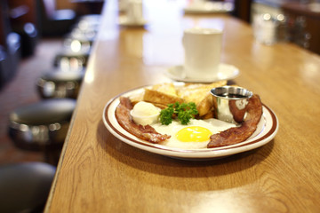 A breakfast of French toast, bacon, and an egg