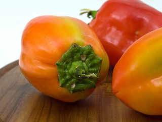 Colorful paprikas on wooden kitchen board isolated