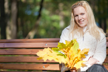 Girl sits on a bench and smiles autumn day