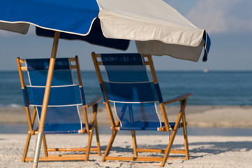 two blue beach chairs with umbrella on beach