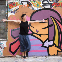 Jeune femme s'étirant devant un mur couvert de graffitis