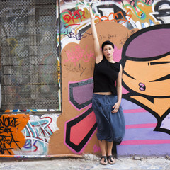 Jeune femme levant un bras devant un graffiti