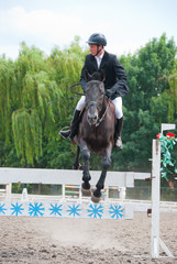 Jockey jumps over a hurdle
