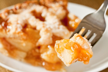 Bite of delicious rustic apple pie on a fork
