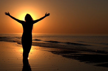 Young adult female with arms wide open on a sunset