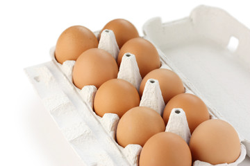 Brown eggs in carton on white background