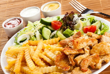 Grilled meat, French fries and vegetables