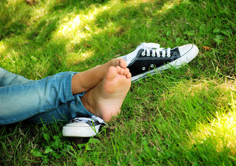 feet of the girl teenager and gym shoes on a green grass of a la