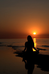 Fototapeta premium Woman meditating at the sunset