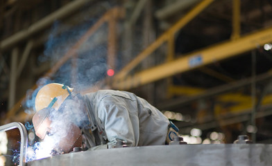 Heavy industry manual worker welding/grinding in a factory - obrazy, fototapety, plakaty