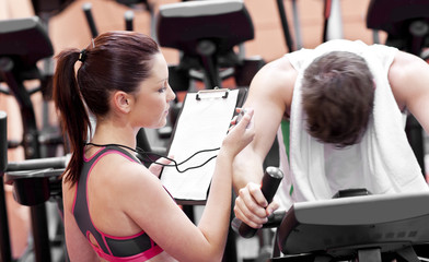 Female coach using a chronometer while man is on bicycle