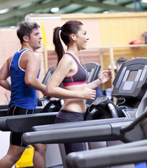 Fototapeta premium Healthy couple running on a treadmill in a sport centre