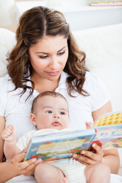 Attentive mother reading a book to her adorable baby