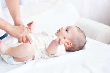 Close-up of a young mother changing the nappy of her baby lying