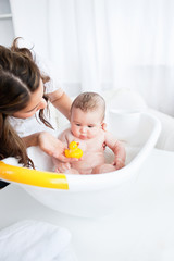 Obraz na płótnie Canvas Piękne matki dając jej kąpiel dziecka