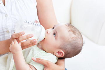 Peaceful baby boy lying in his mother's arms drinking milk