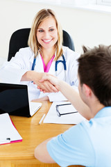 Friendly female doctor shaking hands with patient in office