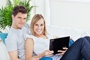 Young happy couple lying on the sofa with laptop