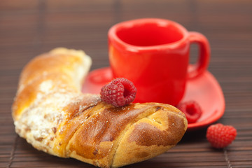 Cup with a plate , raspberry and roll on a bamboo mat