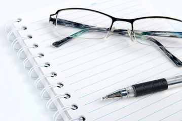 Pen,notebook and glasses on white background